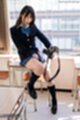Momoki nozomi sitting on desk wearing uniform holding camera knee raised.jpeg
