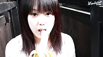 Machiko licking tip of peeled banana