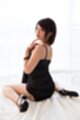 On her knees wearing black dress in high heels looking back