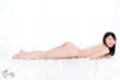 Lying on her front nude smiling broadly pert ass