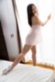 Standing against window looking back stretching leg out wearing high heels