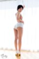Standing in front of curtained window topless in shorts high heels