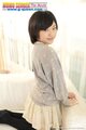 Mei kadowaki kneeling on couch looking past her shoulder short hair frames her pretty smile wearing short skirt