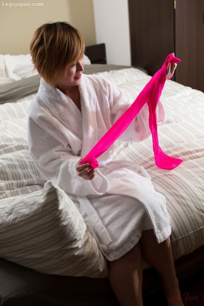 Sitting on bed wearing robe stretching pink pantyhose
