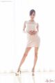 Hands clasped wearing white dress in high heels