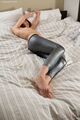 Lying on bed arms raised wearing leggings bare feet pressed together