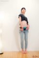 Standing against wall lowering jeans bare feet