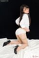 On her knees looking over her shoulder raising skirt over panties wearing black high heels