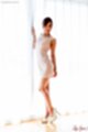 Wearing white dress at curtained window in high heels