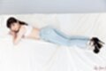 On her front looking up legs stretched out in jeans high heels