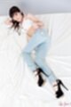 Lying on her side knee raised wearing jeans black high heels